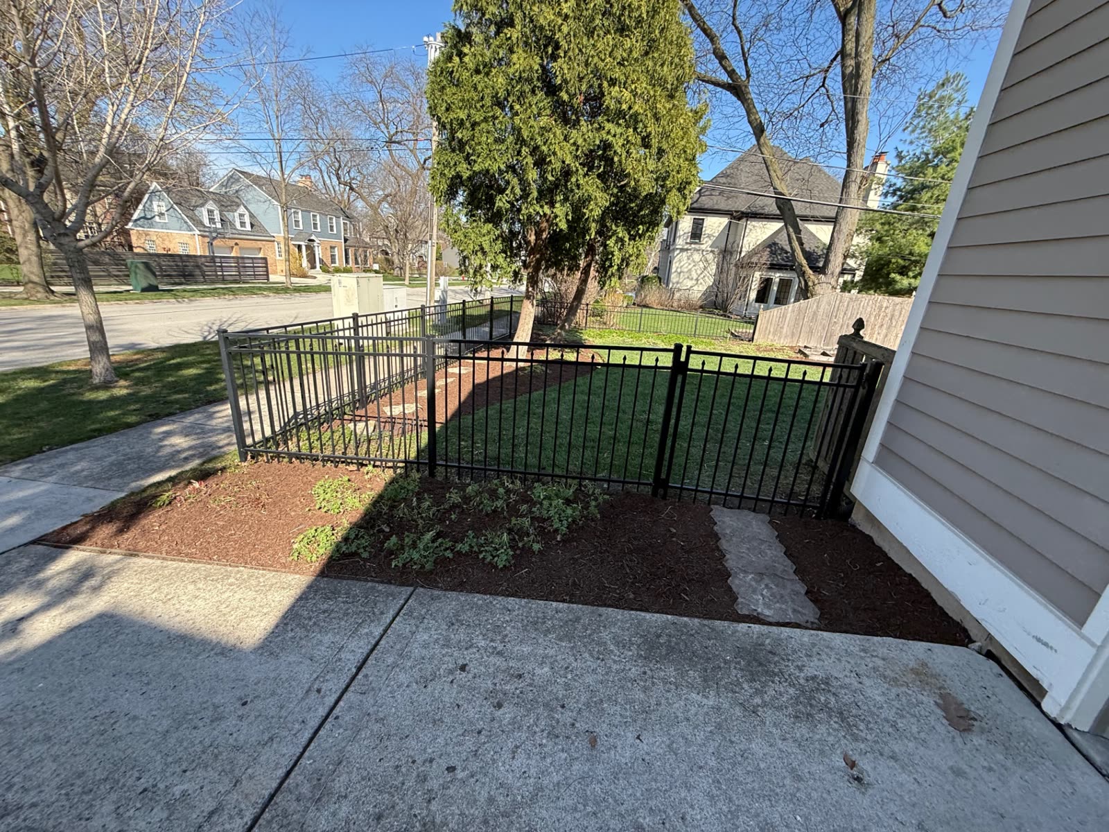 Black metal fence with a mulch bed and stepping stones