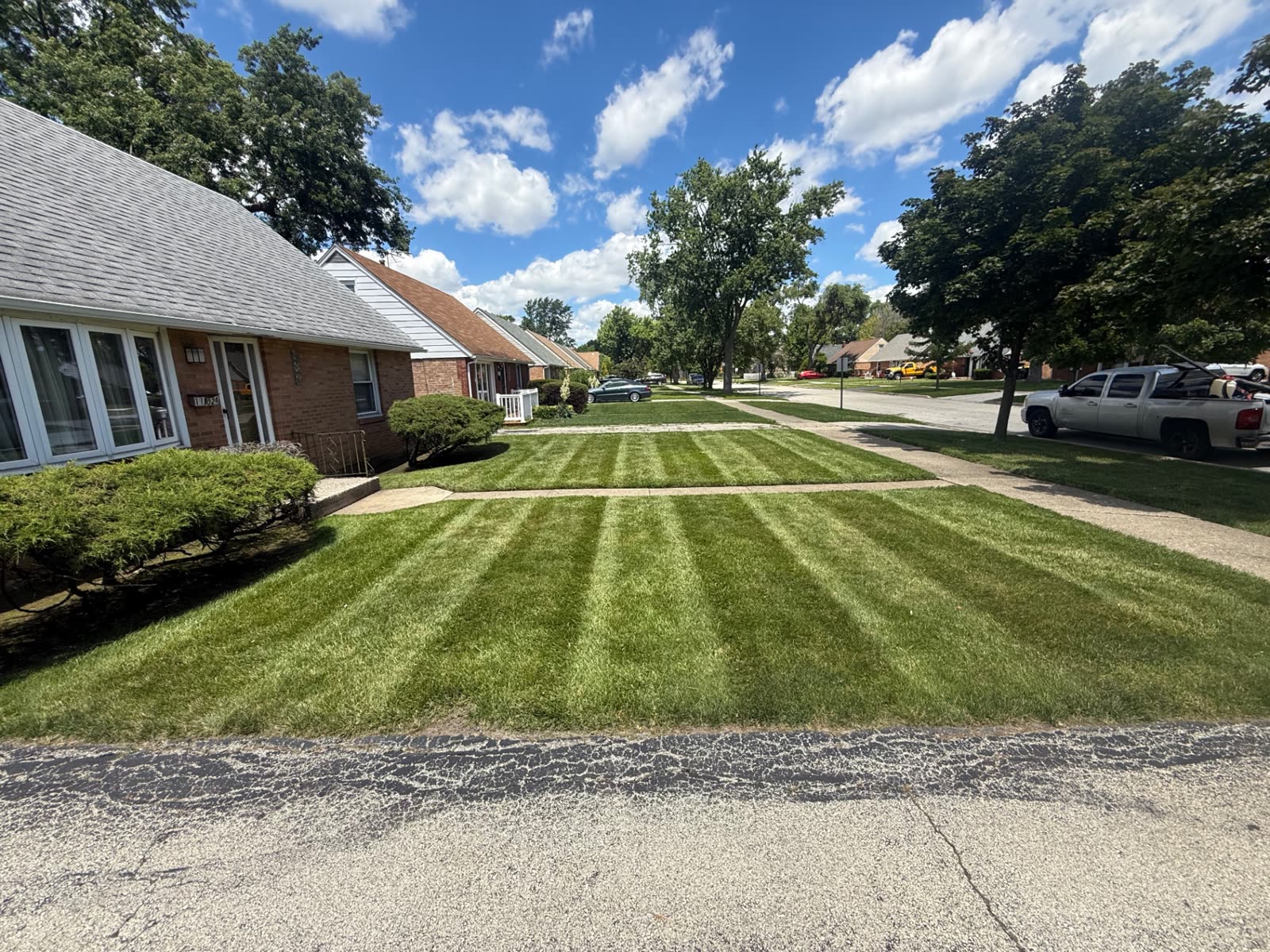 Front lawn with crisp mowing stripes beside a brick house