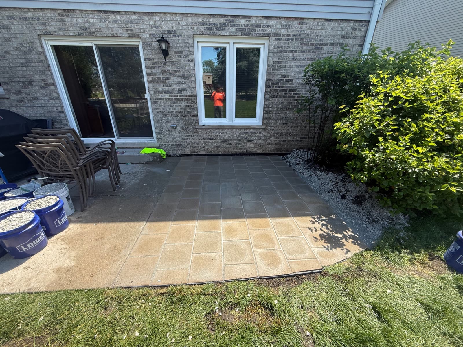 Paver patio being laid beside a brick house