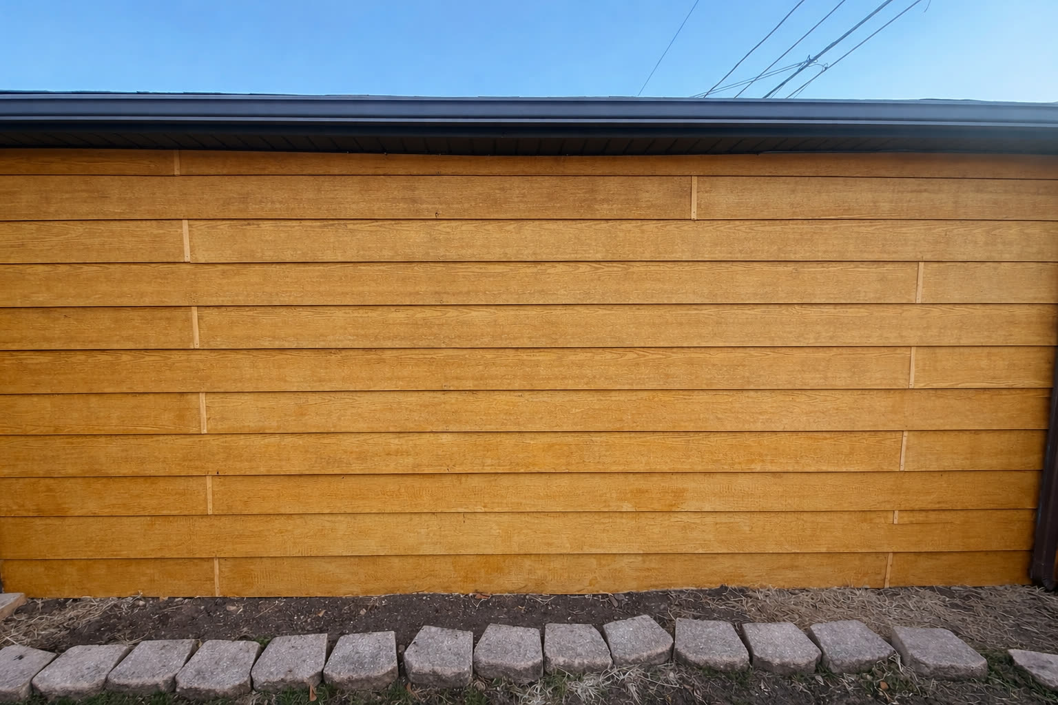 Wood fence mid-stain, showing new finish against the weathered boards