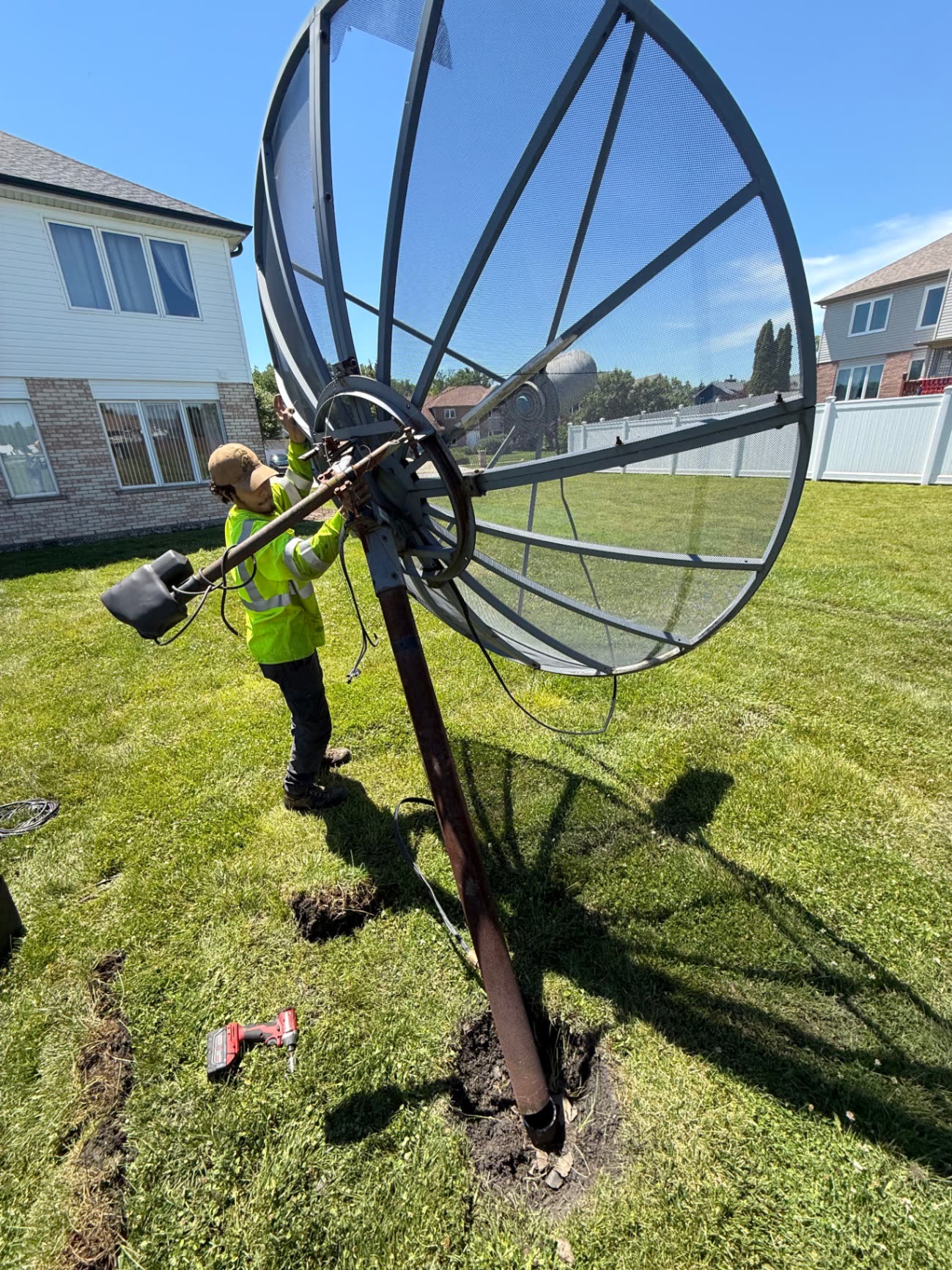 Crew removing a large satellite dish from a yard